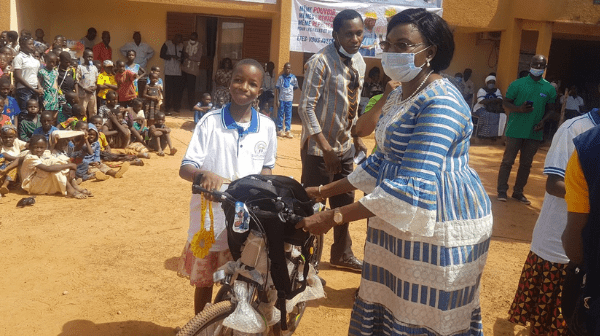 Übergabe von Schulmaterial und einem Fahrrad an einer Schülerin in Bazega, Burkina Faso © FDC / Enfants du Monde